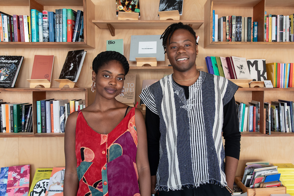 Bomani McClendon (right) and Neta Bomani (left) in front of a bookshelf at Pioneer Books.